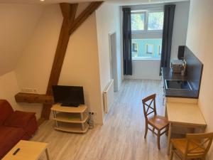 a living room with a couch and a table with a tv at Ferienwohnungen im Stollenhof in Schnelldorf