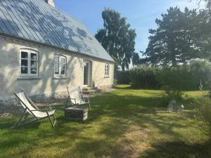 BallenNature Retreat With Sea View Near Ballen On Samsø的院子里的白色房子,带两把椅子