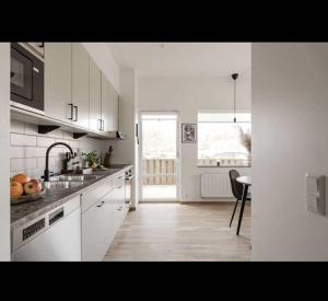 a white kitchen with a sink and a table at Lägenhet mitt i Kungshamn in Kungshamn +11 photos