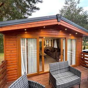 a small cabin with two wicker chairs on a deck at Happy Ever After Lodge in Morpeth
