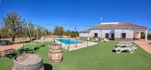 a house with a yard with a pool and some barrels at Casa Rural Entre Almendros in El Toboso