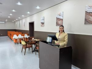 a woman is standing at a counter in a room at Damir HOTEL ГОСТИНИЦА in Aktobe