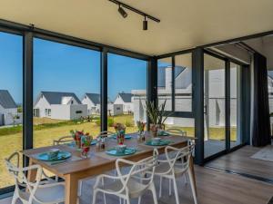 una sala da pranzo con tavolo, sedie e ampie finestre di St Francis Links - Villa Avenue Studio Apartments a St Francis Bay