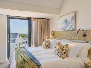 una camera da letto con un letto bianco con una grande finestra di St Francis Links - Villa Avenue Studio Apartments a St Francis Bay
