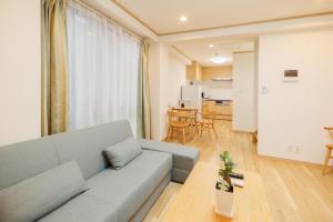 東京にあるHotaku HOTEL Akihabaraのグレーのソファのあるリビングルームとキッチン