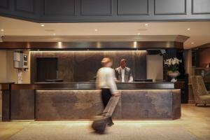 a man walking past a bar in a hotel lobby at Donnington Hotel, Spa & Golf in Newbury +54 photos