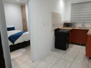 a room with a bed and a kitchen with a sink at Russell's Rest Apartments in Johannesburg