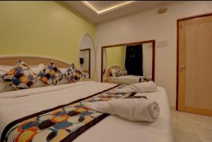 Un dormitorio con dos camas y un gran espejo. en Hotel Stay Land Inn Versova, en Bombay