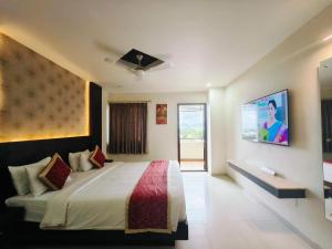 a bedroom with a bed and a tv on the wall at Holiday Residency Coimbatore in Coimbatore