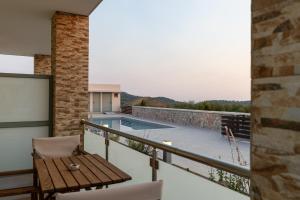 a balcony with a wooden table and a swimming pool at QUERCUS Boutique Living in Valanidorachi