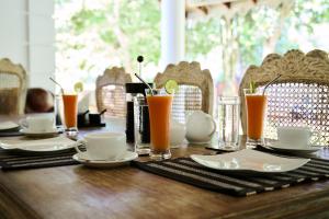 a wooden table with plates and glasses of orange juice at Kalukanda House in Weligama