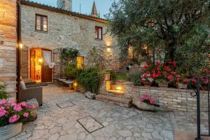 a stone house with flowers in a courtyard at Historic Village With Pool Near Todi in Todi