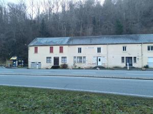 a large white building with red windows on the side of a road at Logement rustique pont de menat les gorges de la Sioule in Menat