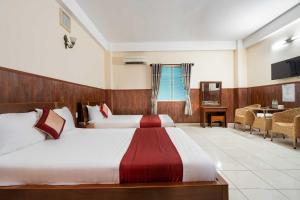 a hotel room with two beds and a table at Dancenter Phuong Nam Hospital Formerly Nam Phuong Hoang Hau in Ho Chi Minh City