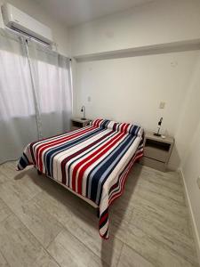 a bedroom with a bed with a striped blanket on it at Urbanstay in Villa Constitución +5 photos