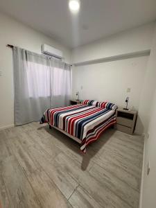a bedroom with a bed with a striped comforter at Urbanstay in Villa Constitución