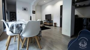 a dining room with a table and white chairs at La terrasse, proche des places 2 chambres in Arras