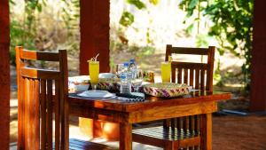 a wooden table with food on it with two chairs at Jungle Crown Cabin in Sigiriya +46 photos