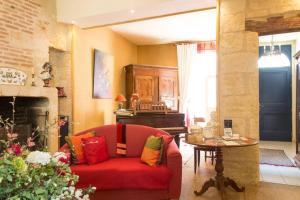 a living room with a red couch and a piano at B&B La Closeraie in Vouvray