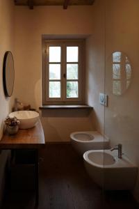 a bathroom with two sinks and a toilet and a window at Restored Farmhouse In Tuscan Casentino Hills in Poppi
