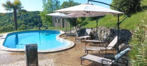 a swimming pool with chairs and an umbrella at Le Hameau Saint-Julien in Engayrac