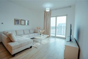 Una sala de estar blanca con un sofá y un televisor. en Modern 1BR with Lake View Yas Island Stay for 4, en Abu Dabi