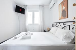 1 dormitorio con 1 cama blanca y TV. en Minimal Apt in the Heart of the city, en Tesalónica