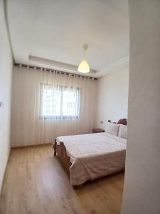 Un dormitorio blanco con una cama grande y una ventana. en Cozy Studio Vue sur Piscine à Ocean Park Zenata City Eco, en Aïn Harrouda