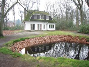 a house with a reflection in a body of water at Westmalle Forest Garden Home in Zoersel +21 photos