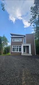 a large brown house with a lot of windows at Le repaire du hibou - Piano & Spa in Petite-Rivière-Saint-François