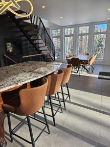 a dining room with a table and chairs and a staircase at Le repaire du hibou - Piano & Spa in Petite-Rivière-Saint-François