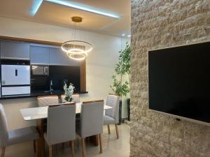 a dining room with a table and a flat screen tv at APARTAMENTO NA PRAIA CENTRO De BERTIOGA in Bertioga