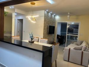 a kitchen and living room with a table and chairs at APARTAMENTO NA PRAIA CENTRO De BERTIOGA in Bertioga