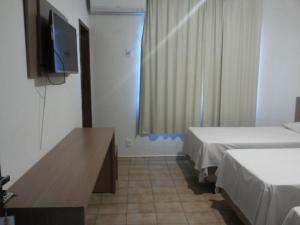 a room with two beds and a flat screen tv at Hotel Real Trevo in Montes Claros