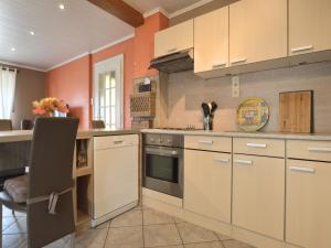 a kitchen with orange walls and white cabinets at Waimes Retreat Near Forest in Waimes