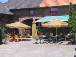 a patio with umbrellas and tables and chairs and a building at McMüller's Brauereigasthof in Kofferen