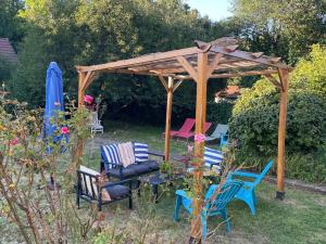 a wooden gazebo with chairs and a table at Chambre Océan, parking gratuit et jardin in Besançon