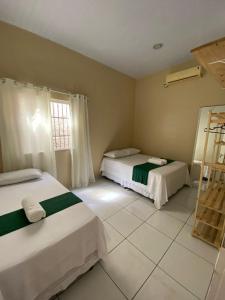 a bedroom with two beds and a window at Casa Lardeira in Barreirinhas