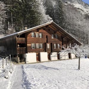 a log cabin with snow on the ground in front at Brachli in Innertkirchen