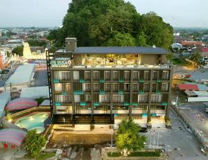 a large building with a pool in front of it at Elissa Hotel & Suites in Kangar