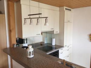 a kitchen with white cabinets and a granite counter top at Haus Am See in Därligen