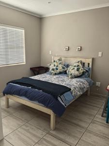 a bedroom with a bed with blue sheets and pillows at The Pearl in Pearly Beach