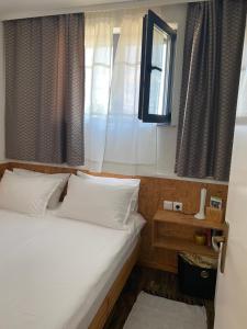 a bedroom with a bed with white pillows and a window at Studio apartman Gradna in Samobor