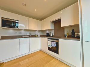 una cucina con mobili bianchi e pavimento in legno di Modern Central Apartment with Parking a Cambridge