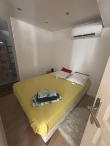 a small bedroom with a bed with a yellow blanket at Location moderne plein pied Sanary sur mer 4 pers max Léchappée belle 7 minutes en voiture du centre ville port marché et plages grand espace extérieur parking gratuit in Sanary-sur-Mer