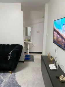 a living room with a black couch and a flat screen tv at Wonderstay D in Nairobi