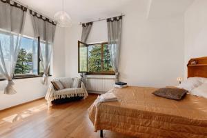 een slaapkamer met een bed, een stoel en ramen bij La Squazza in Bertigaro