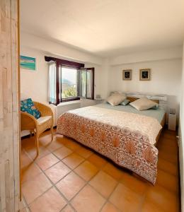 a bedroom with a bed and a chair and a window at Casa Leyian - Brissago in Brissago