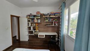 a room with a desk and a table and a window at Quarto expetacular in Timóteo