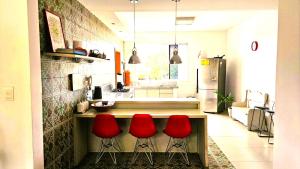 a kitchen with three red stools in front of a counter at Quarto expetacular in Timóteo